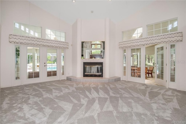 unfurnished living room with carpet, high vaulted ceiling, and french doors