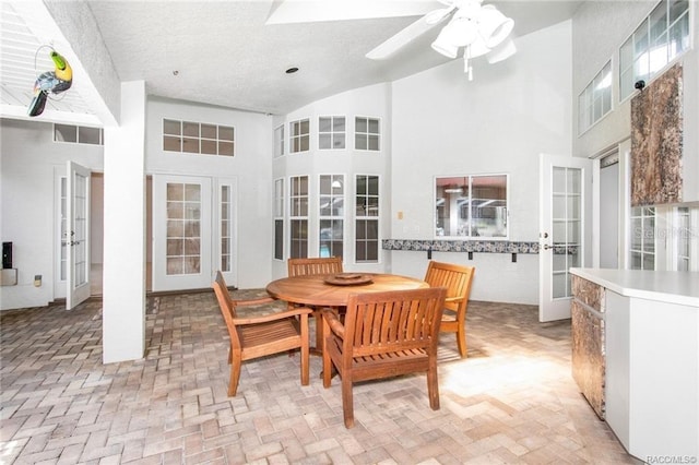 dining area with ceiling fan, a towering ceiling, and french doors