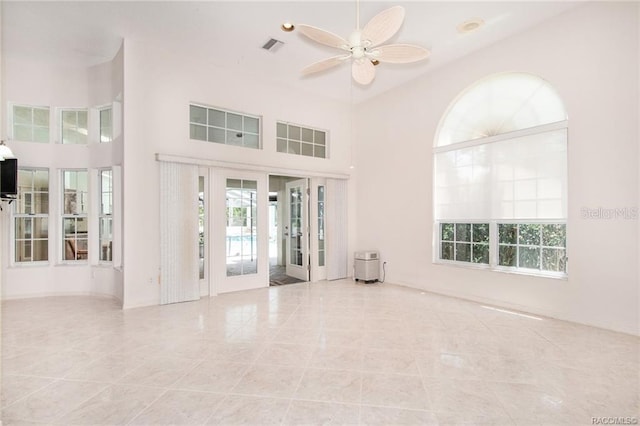 interior space with ceiling fan, plenty of natural light, a towering ceiling, and light tile patterned floors