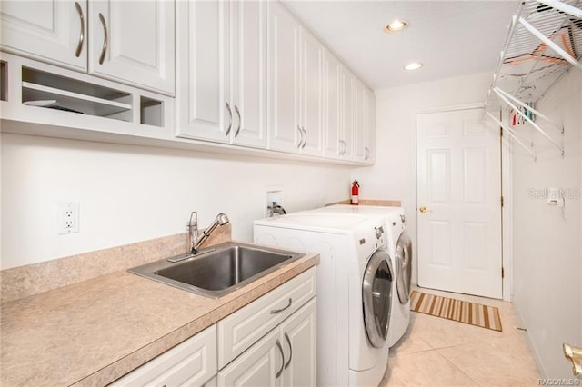 washroom with light tile patterned flooring, cabinets, sink, and washing machine and clothes dryer