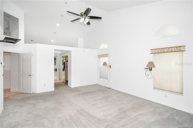 unfurnished living room with ceiling fan, light colored carpet, and high vaulted ceiling