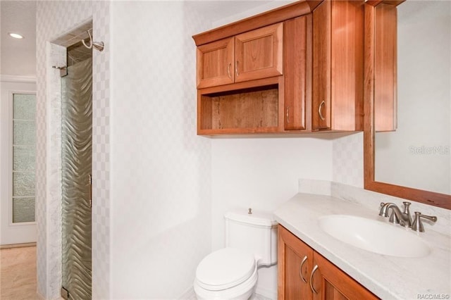 bathroom with tiled shower, vanity, and toilet