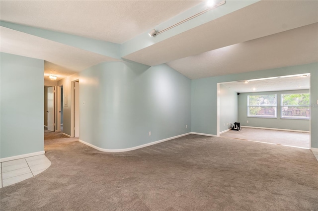 carpeted empty room with a textured ceiling and vaulted ceiling