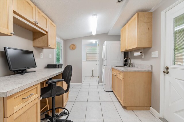 kitchen with plenty of natural light, built in desk, lofted ceiling, and stacked washer and dryer