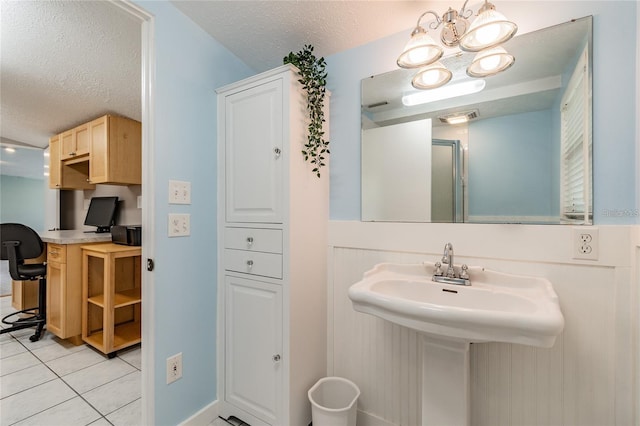 bathroom with tile patterned floors, sink, and a textured ceiling