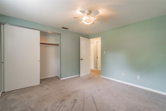 unfurnished bedroom featuring light carpet, a closet, and ceiling fan