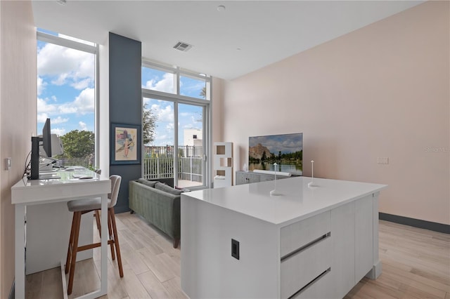 kitchen with a breakfast bar area, white cabinets, an island with sink, and light wood-type flooring