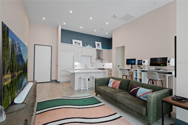 living room with a towering ceiling and light hardwood / wood-style floors