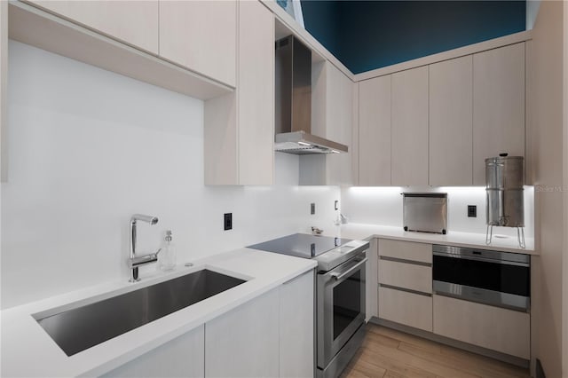 kitchen with electric stove, sink, oven, wall chimney exhaust hood, and light hardwood / wood-style flooring