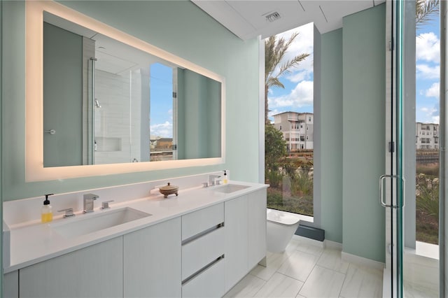 bathroom featuring an enclosed shower, vanity, plenty of natural light, and toilet