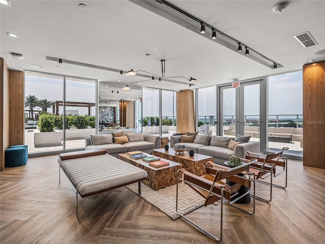 living room featuring parquet floors, expansive windows, track lighting, and a wealth of natural light