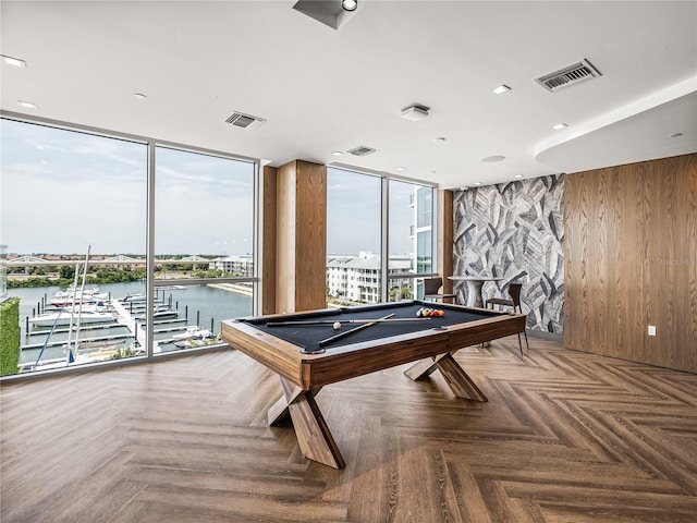 game room with a water view, billiards, wooden walls, and parquet flooring