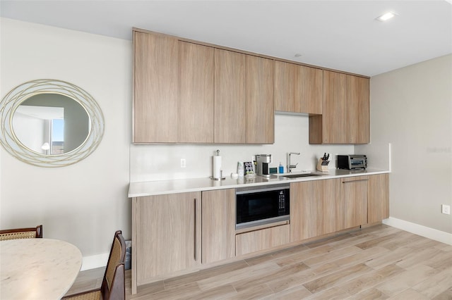 kitchen with black microwave, sink, and light brown cabinetry