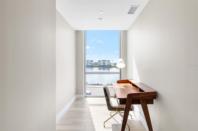 interior space featuring a water view, a wall of windows, and light hardwood / wood-style floors