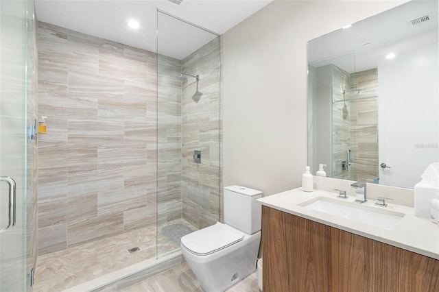 bathroom featuring a shower with door, vanity, and toilet