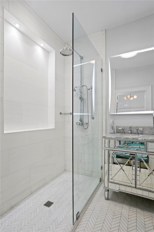 bathroom featuring tile patterned flooring, a tile shower, and sink