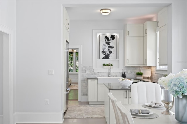 kitchen with decorative backsplash, light tile patterned floors, and white cabinetry