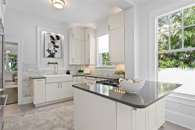 kitchen with white cabinetry, sink, kitchen peninsula, decorative backsplash, and light tile patterned floors