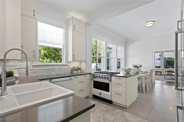 kitchen with kitchen peninsula, tasteful backsplash, high end stove, sink, and white cabinetry