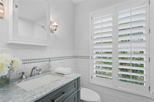 bathroom with vanity, toilet, and tile walls