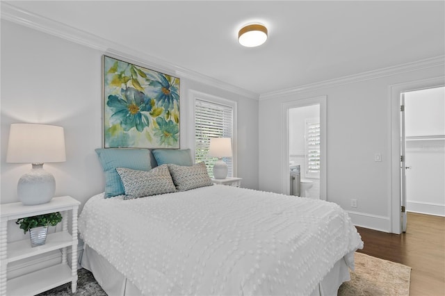 bedroom with ensuite bath, a spacious closet, dark hardwood / wood-style floors, crown molding, and a closet