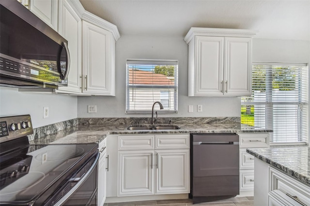 kitchen with dark stone counters, white cabinetry, sink, and stainless steel appliances