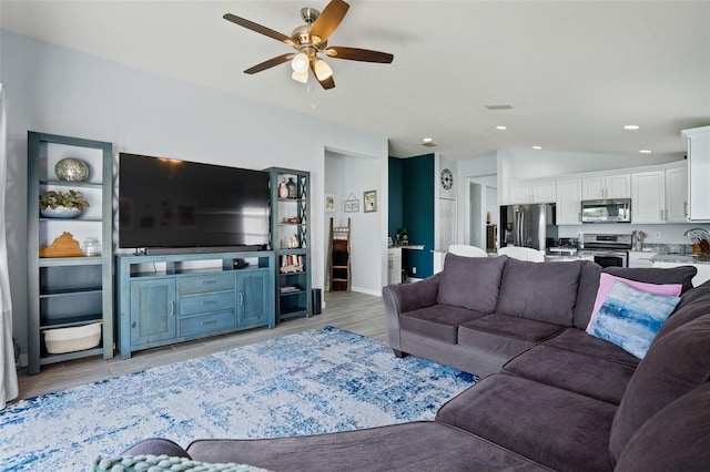 living room with ceiling fan, sink, and light hardwood / wood-style floors