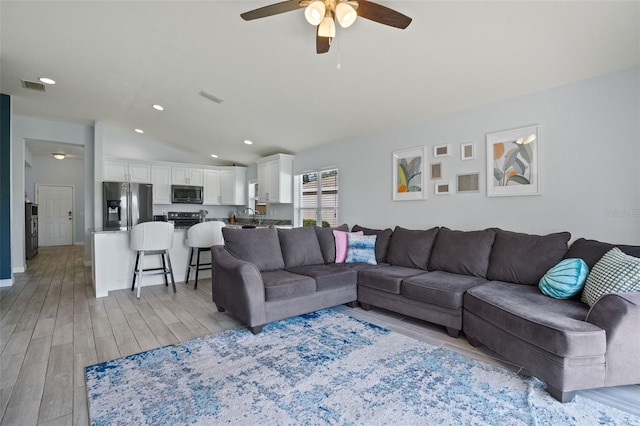 living room with ceiling fan, light hardwood / wood-style floors, and lofted ceiling