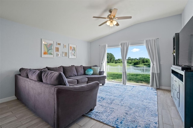 living room with ceiling fan, light hardwood / wood-style floors, and vaulted ceiling