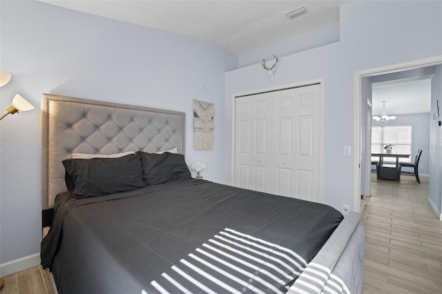 bedroom featuring light hardwood / wood-style floors, an inviting chandelier, vaulted ceiling, and a closet