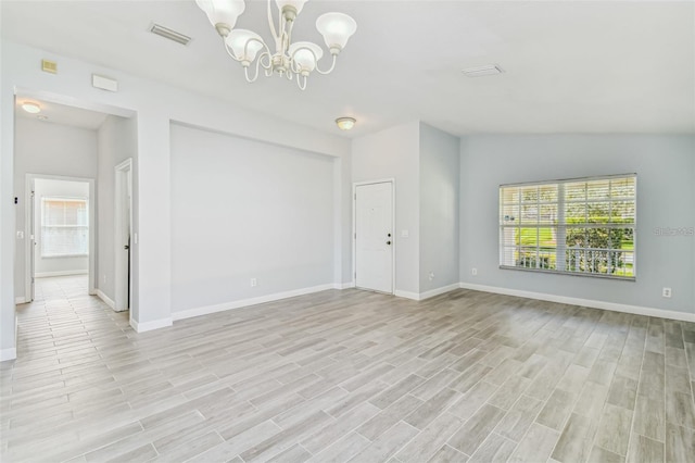 empty room with lofted ceiling, light hardwood / wood-style floors, a wealth of natural light, and a notable chandelier