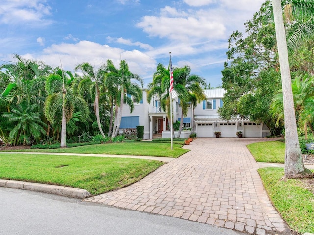 view of front of home featuring a balcony, a front lawn, and a garage