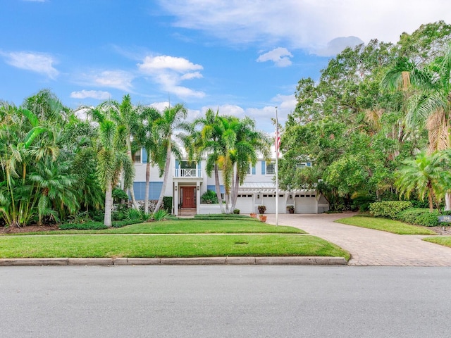 view of front of property with a balcony, a garage, and a front lawn