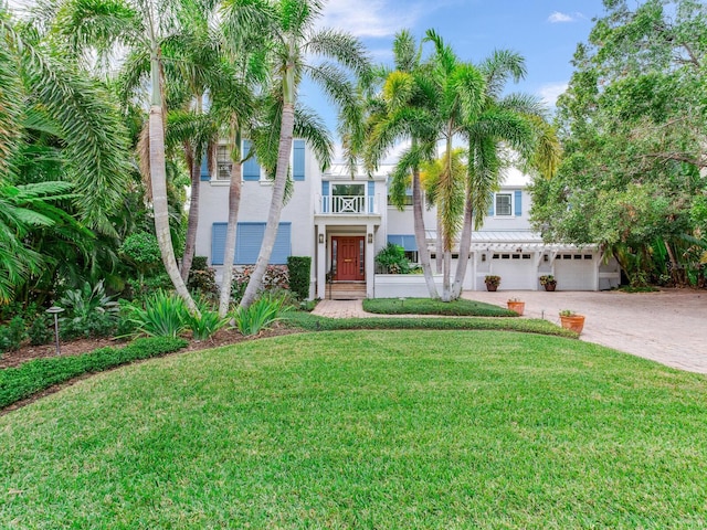 view of front of house featuring a front yard, a balcony, and a garage