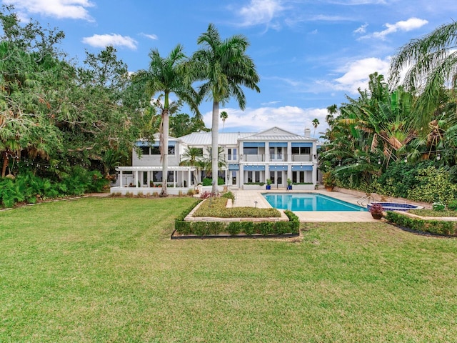 rear view of house with a lawn, a pool with hot tub, a patio area, and a balcony