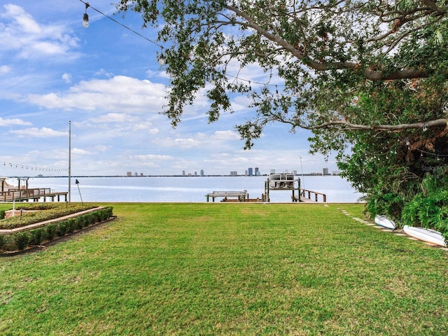 view of dock with a lawn and a water view