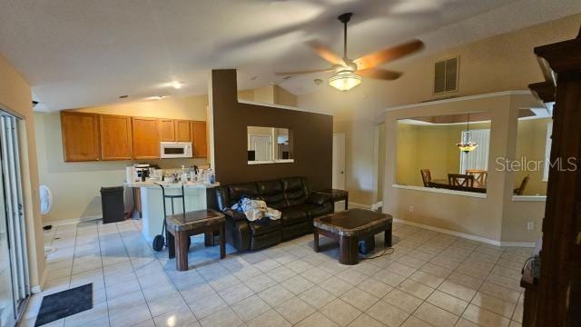 tiled living room with ceiling fan with notable chandelier and vaulted ceiling