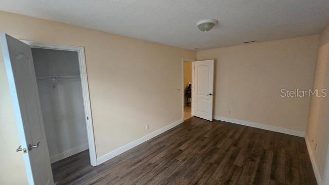 unfurnished bedroom with a closet, dark wood-type flooring, and a textured ceiling