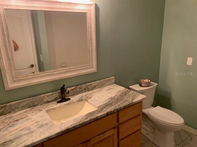 bathroom with toilet, vanity, and tile patterned floors