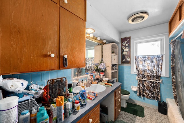 bathroom with vanity, toilet, tile walls, and a healthy amount of sunlight