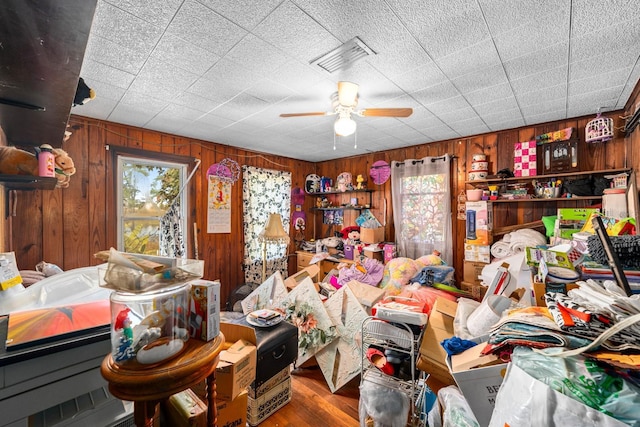 misc room featuring wood walls, plenty of natural light, and ceiling fan