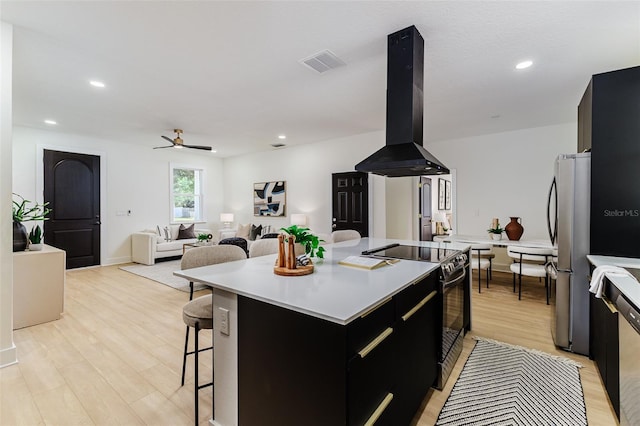 kitchen featuring a center island, black electric range, ceiling fan, stainless steel fridge, and range hood