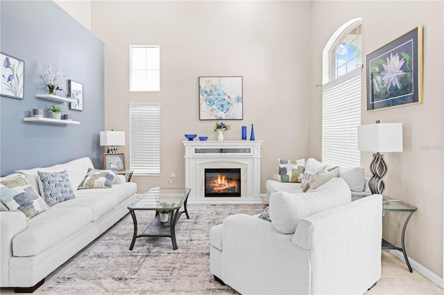 tiled living room featuring a premium fireplace and a high ceiling