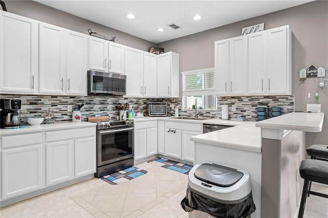 kitchen featuring white cabinets, a kitchen breakfast bar, stainless steel appliances, and tasteful backsplash