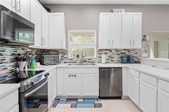 kitchen featuring appliances with stainless steel finishes, backsplash, sink, white cabinetry, and light tile patterned flooring