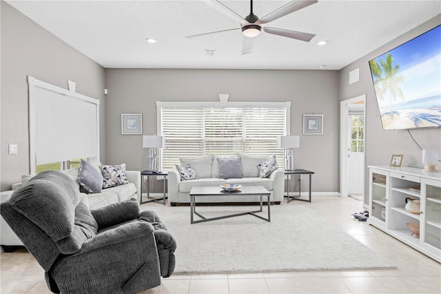 living room featuring ceiling fan, light tile patterned floors, and a textured ceiling