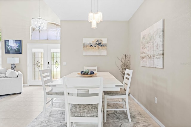 dining space featuring a towering ceiling, french doors, light tile patterned floors, and an inviting chandelier