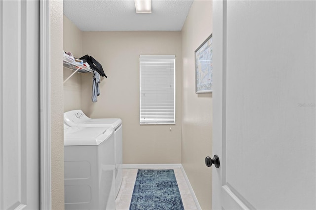 washroom featuring light tile patterned floors, a textured ceiling, and washing machine and clothes dryer