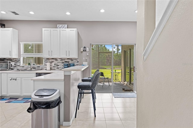 kitchen featuring sink, tasteful backsplash, kitchen peninsula, a breakfast bar area, and white cabinets