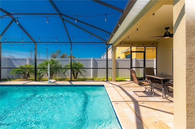 view of swimming pool with ceiling fan, a patio area, and glass enclosure